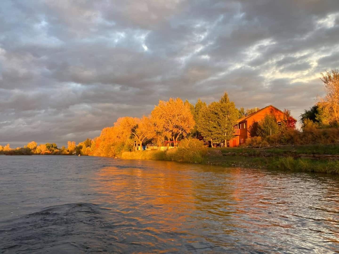 River Edge House glowing beside Henry's Fork at sunset
